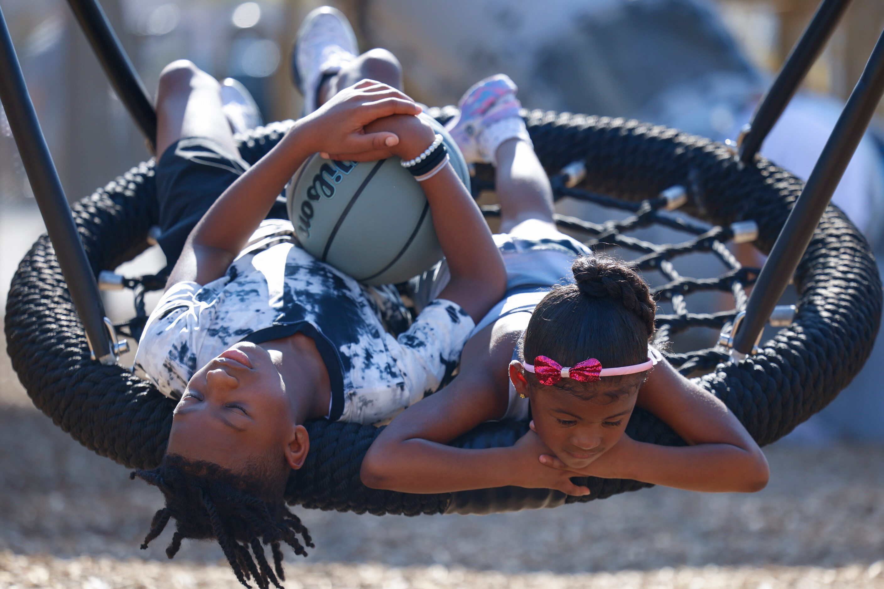 Ashton Gipson, 11, (left), and Aliyah Strange 4, relax on the swing during the opening day...