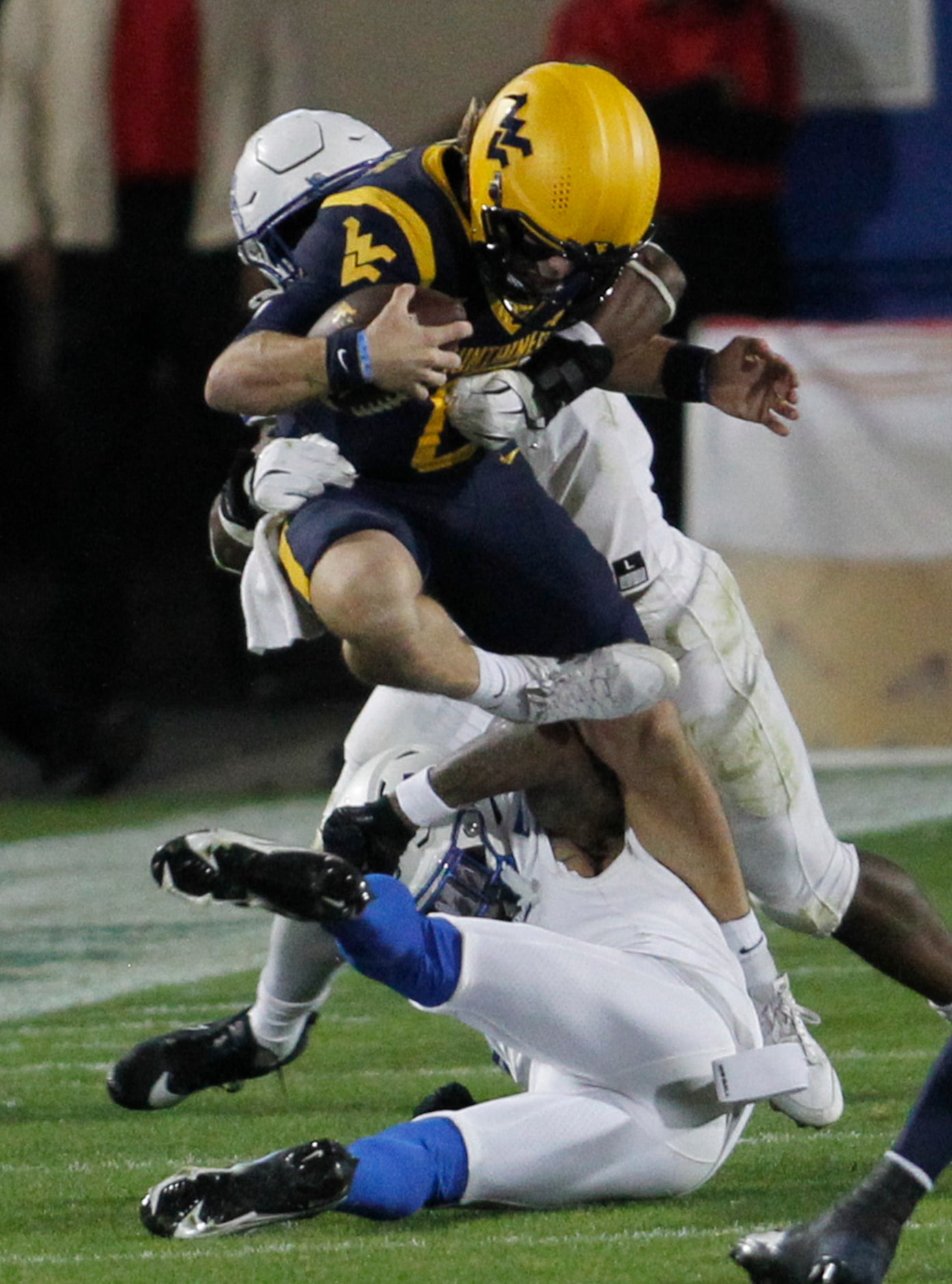 West Virginia quarterback Garrett Greene (6) is tackled by a pair of Memphis defenders...