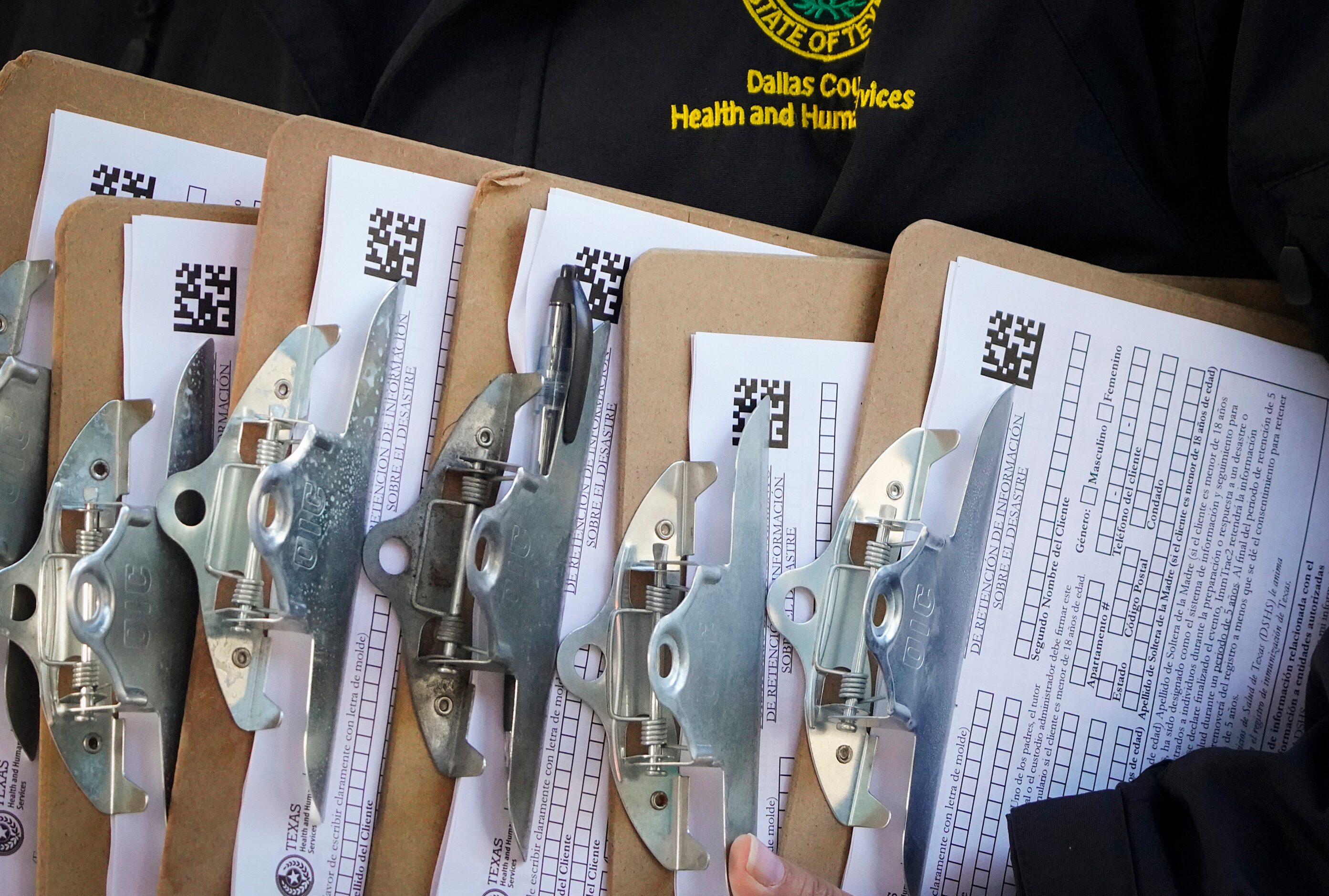 A Dallas County Health and Human Services employee carries a stack of clipboard for...