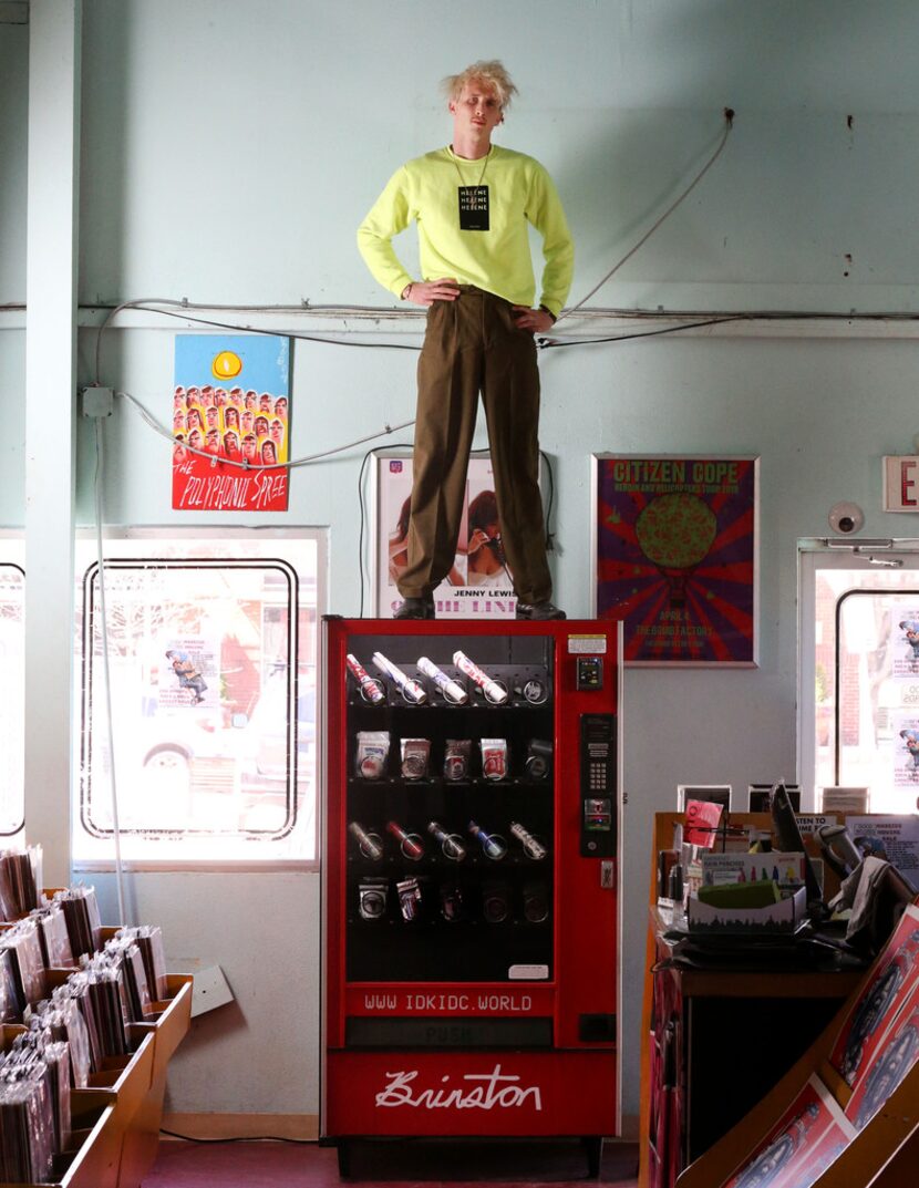 Artist Matthew Brinston poses for a photograph atop his art vending machine at Good Records...