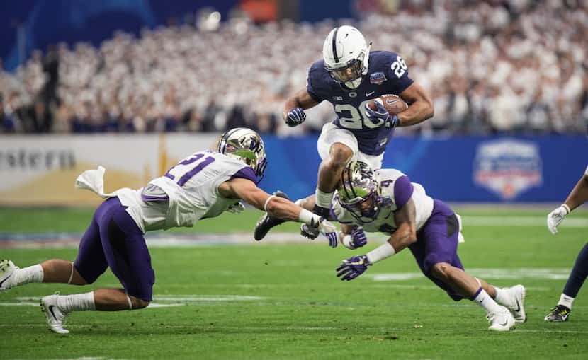 Penn State running back Saquon Barkley goes over the top of Washington defenders Taylor...