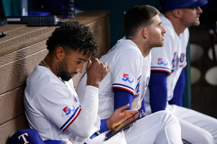 Texas Rangers second baseman Ezequiel Duran studies a tablet in the dugout as he waits for...