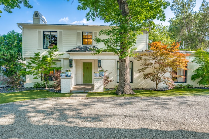 Front exterior of white house with bright green door, gravel driveway