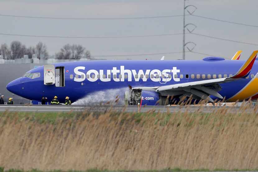 Firefighters spray a Southwest Airlines jet with a damaged engine at Philadelphia...