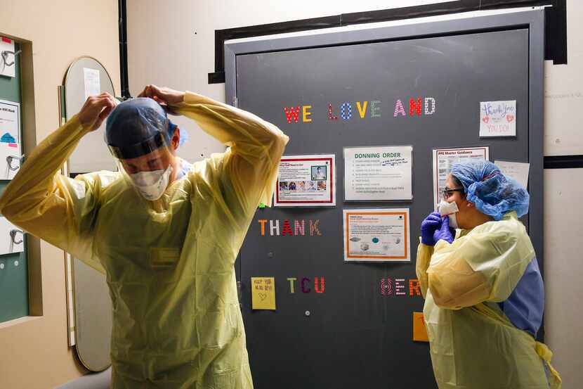 Dr. Drew Saunders and nurse Lily Tredemeyer don personal protective equipment as they...