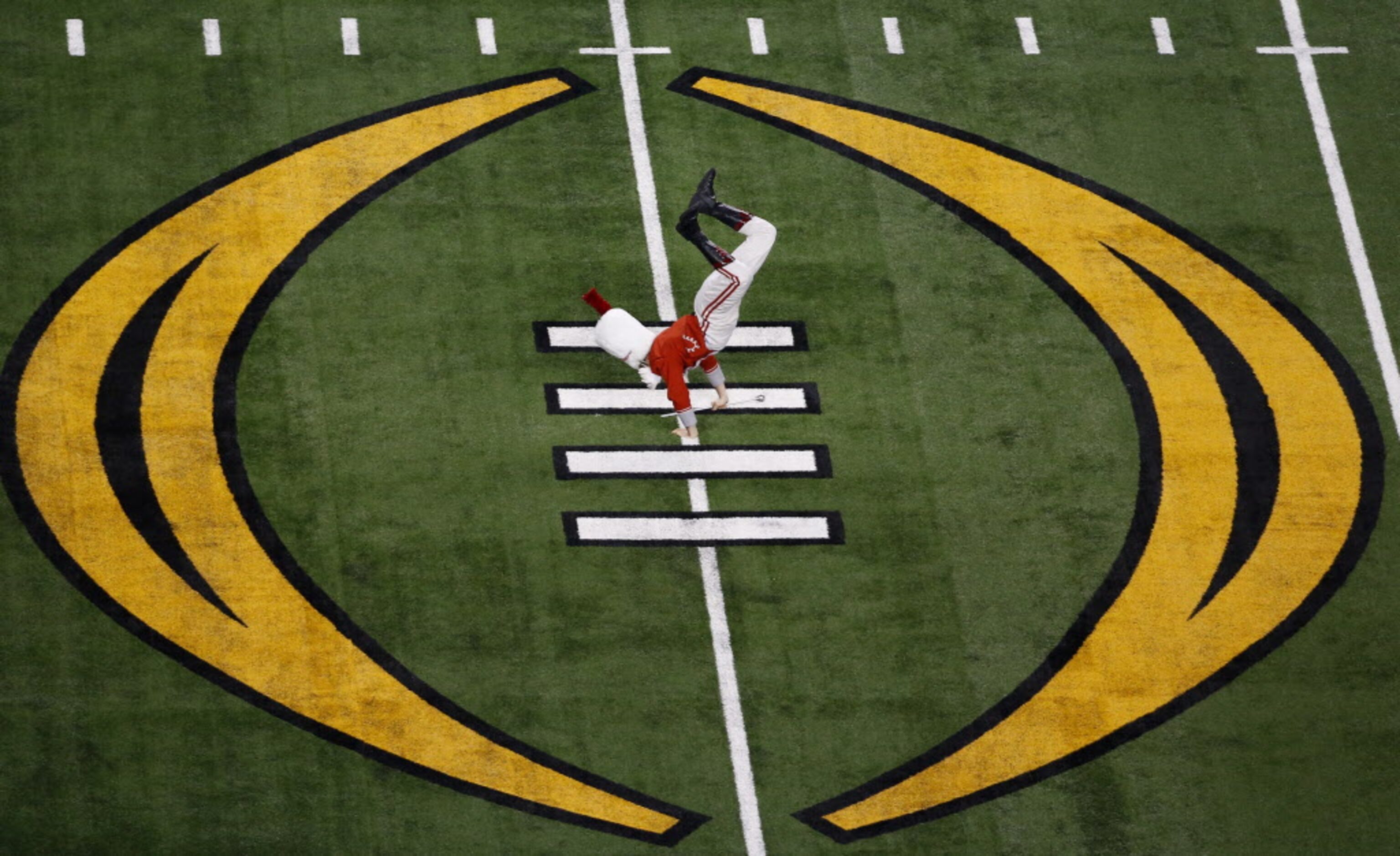 An Ohio State Buckeyes marching band drum major does a flip while performing during the pre...