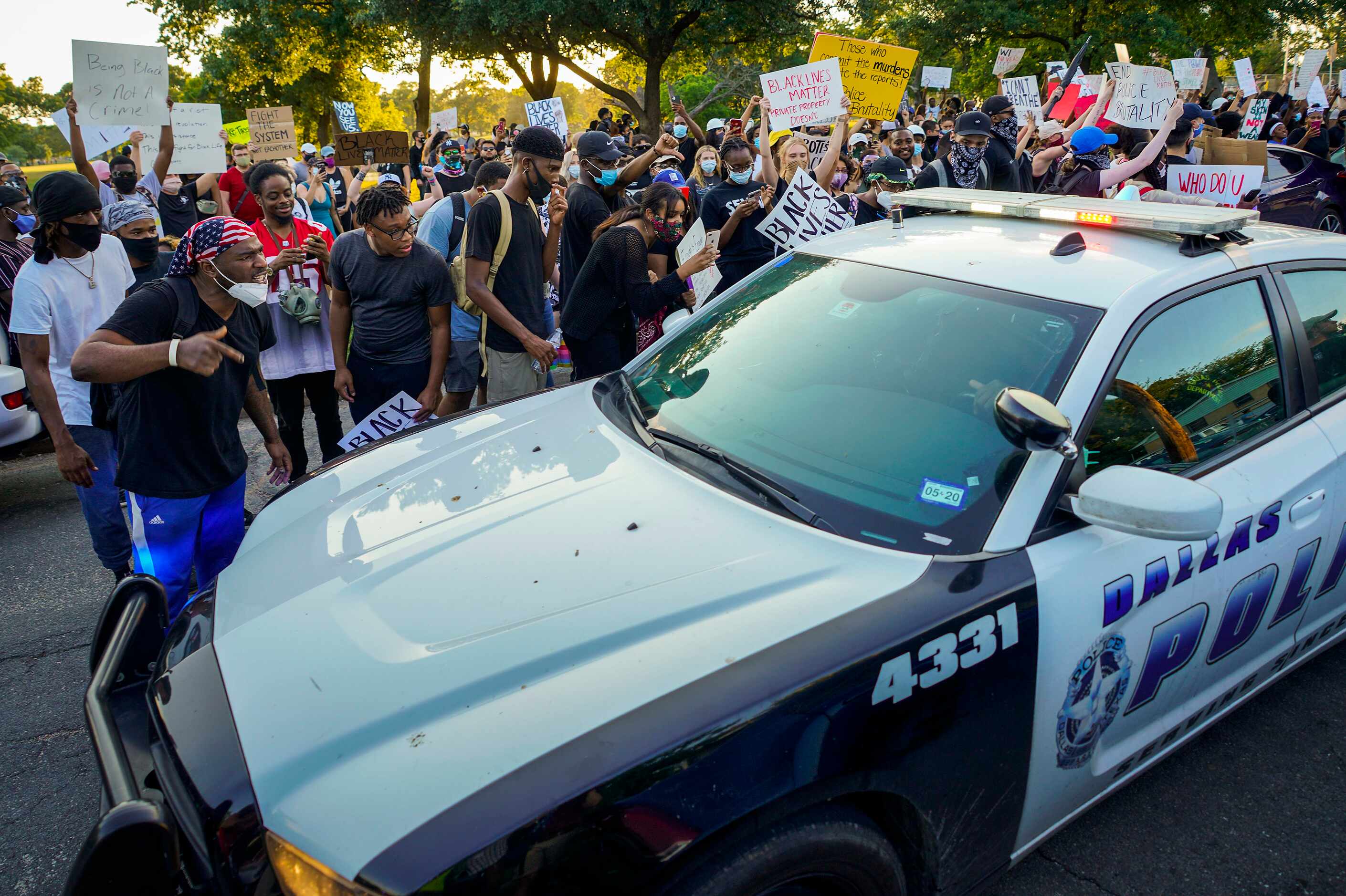 A group of demonstrators yells at a passing Dallas police vehicle at Lake Cliff Park as...