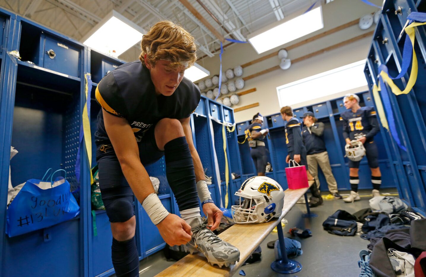 Prestonwood receiver Luke Savage ties his custom cleats in the locker room before the...