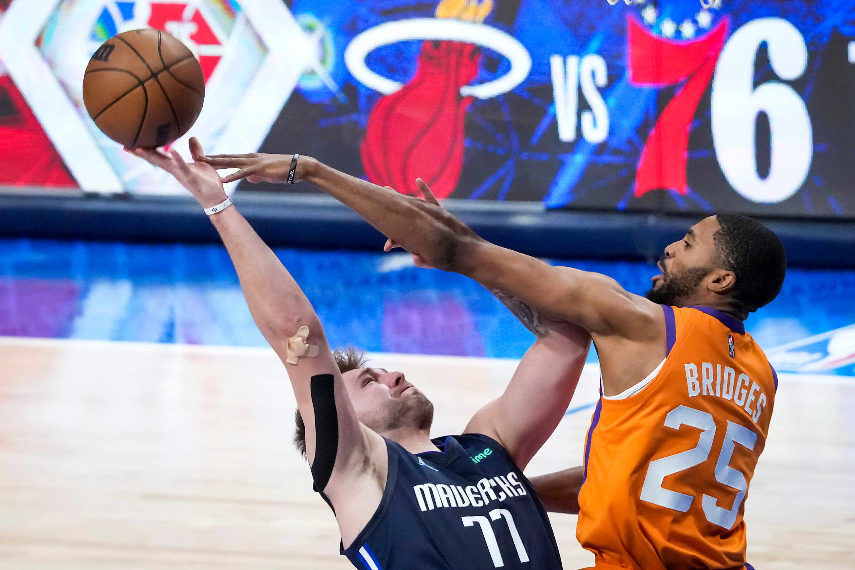 Dallas Mavericks guard Luka Doncic (77) is fouled by Phoenix Suns forward Mikal Bridges (25)...