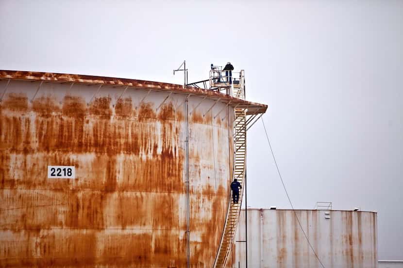 
Workers check a seal on the floating roof of a oil storage tank at the Enbridge tank...