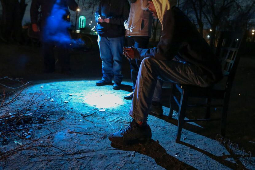 Dallas police detective M. Stampley uses his flashlight to help volunteers Catherine Imes...