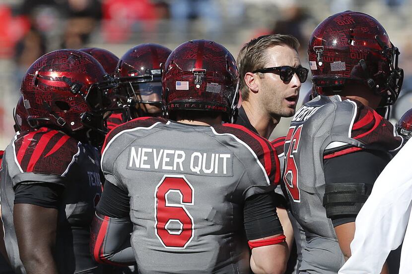 Texas Tech coach, second from right, Kliff Kingsbury speaks with his team during a time-out...