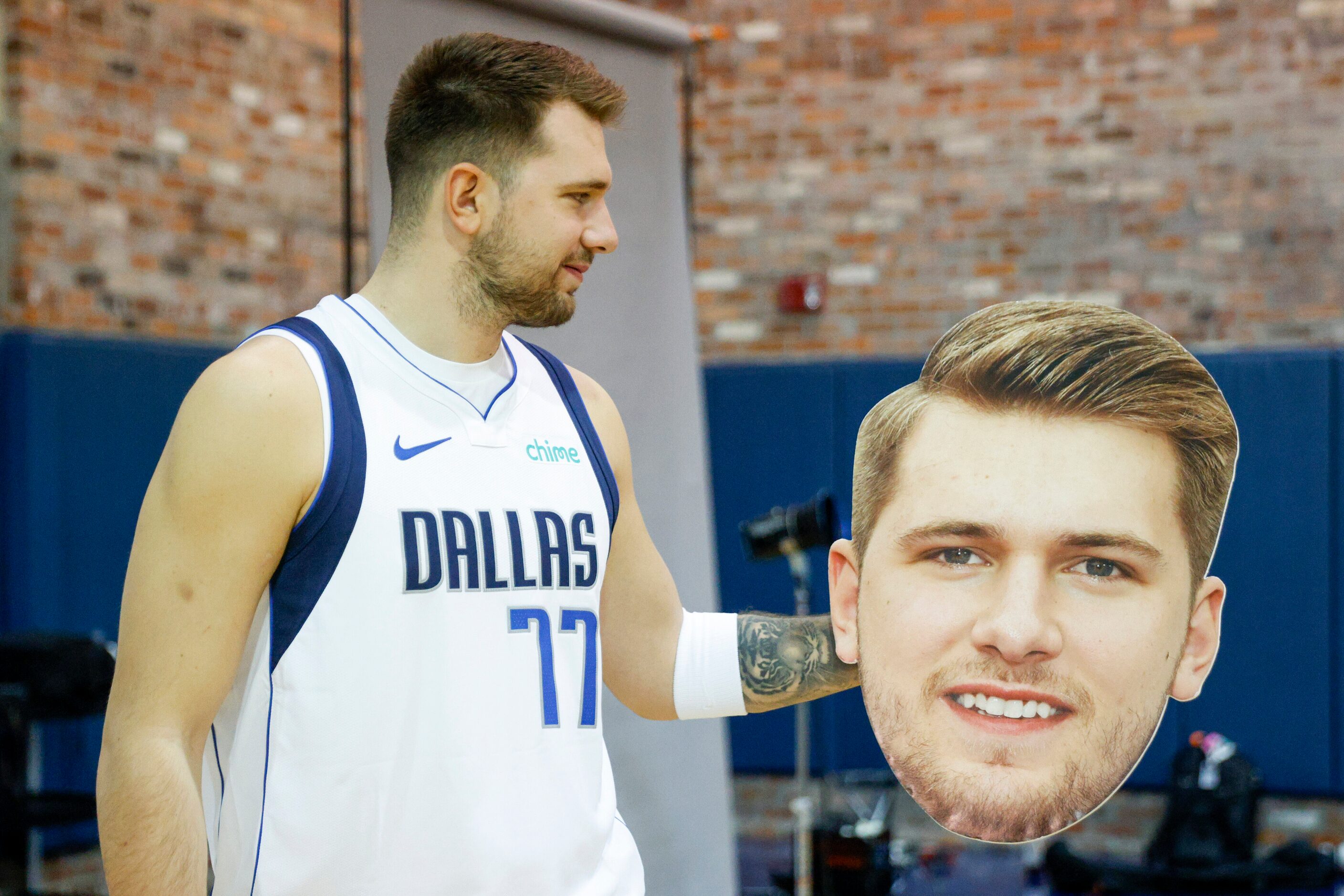 Dallas Mavericks guard Luka Doncic (77) looks at a cutout of his own face during media day...