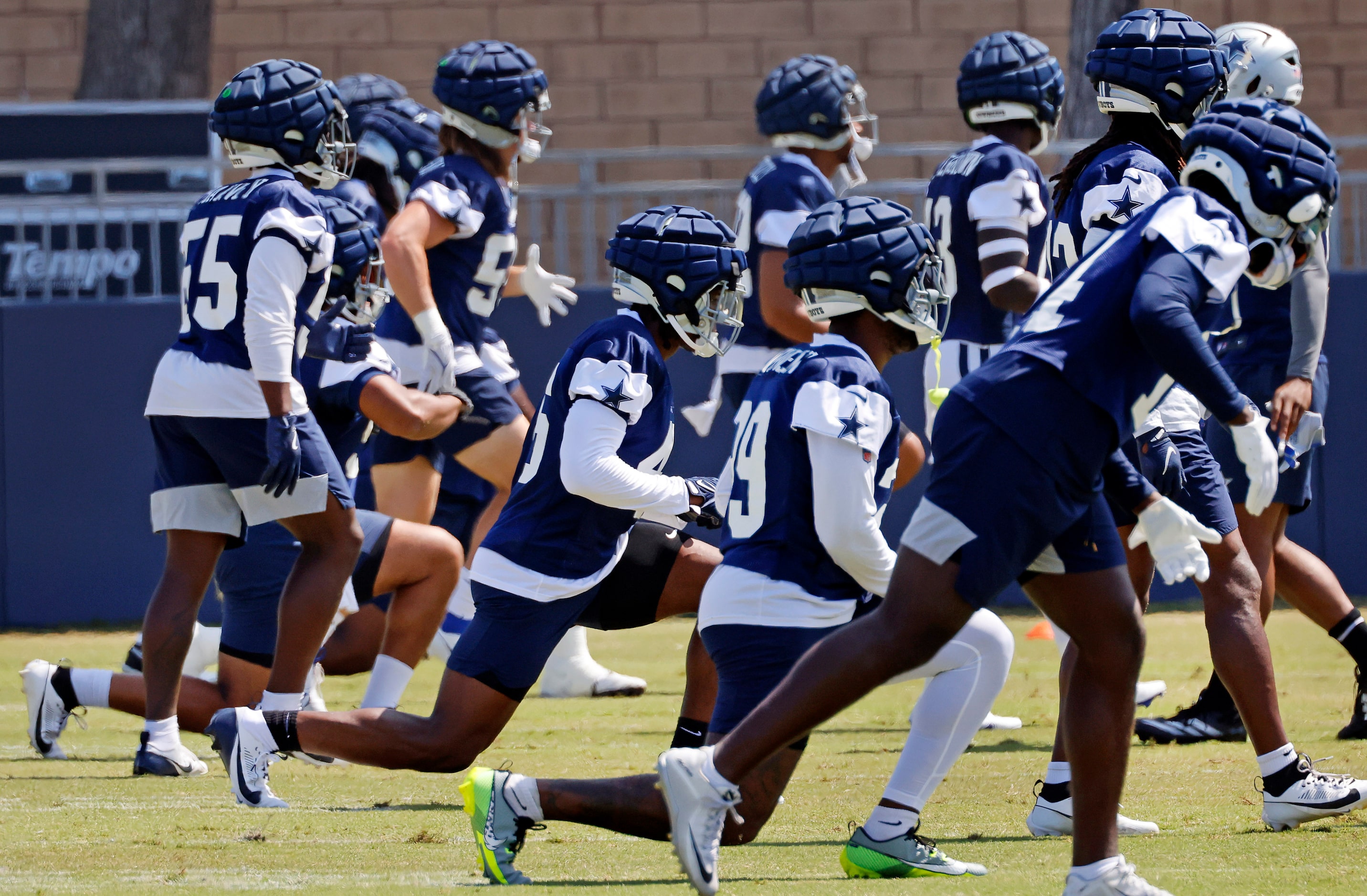 The Dallas Cowboys defense stretches before training camp practice in Oxnard, California,...