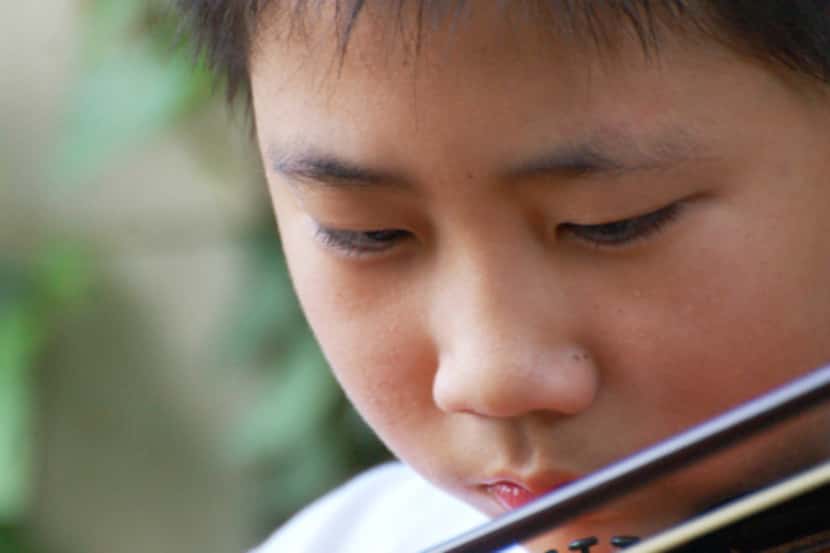 Bohan Zhang, then 12, practicing the violin outside his apartment building in Dallas.