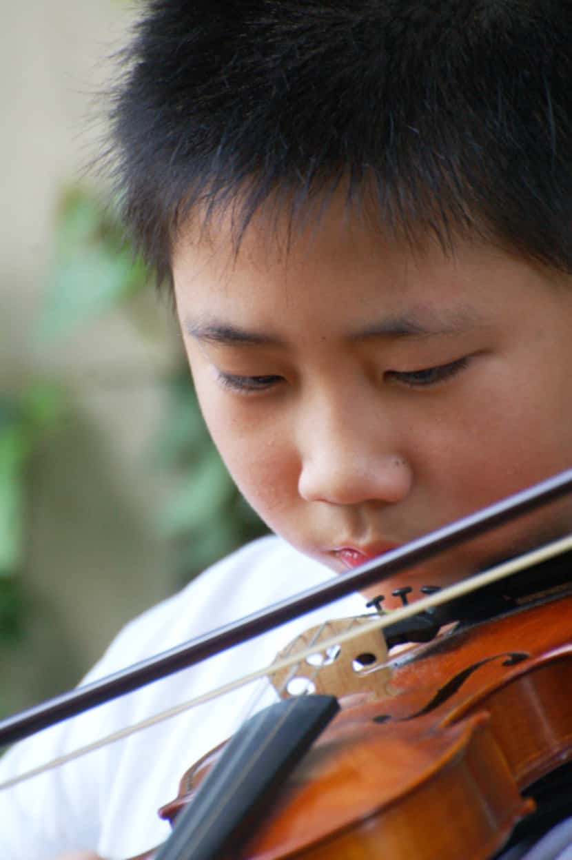 Bohan Zhang, then 12, practicing the violin outside his apartment building in Dallas.