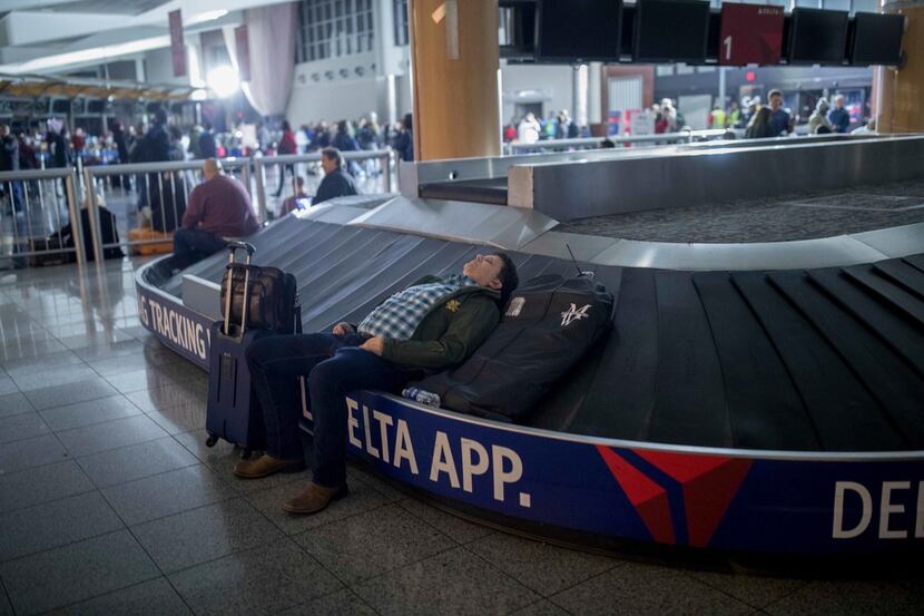 A traveler sleeps on a baggage carousel at Hartfield-Jackson Atlanta International Airport,...