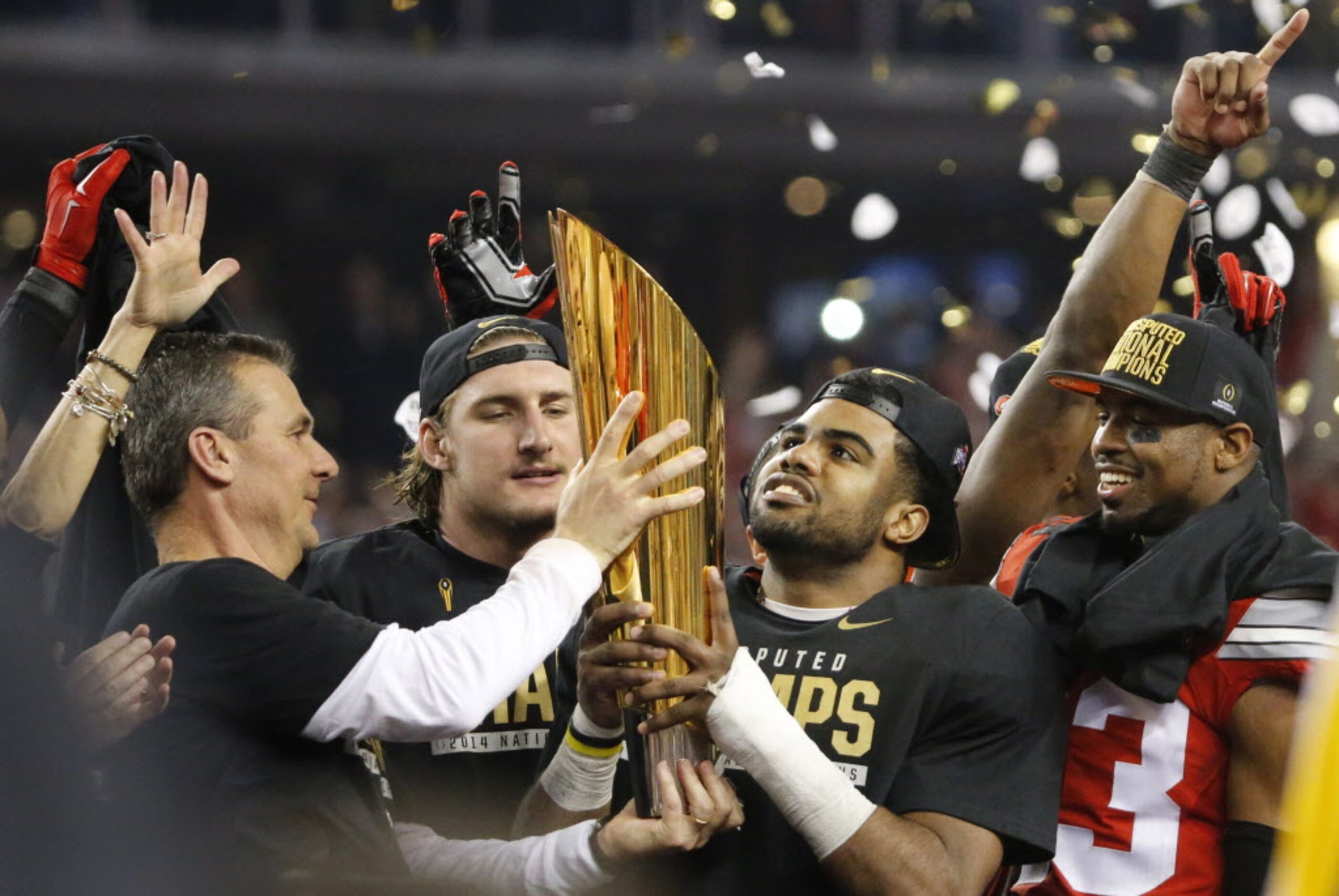 Ohio State head coach Urban Meyer hoists the national championship trophy as running back...