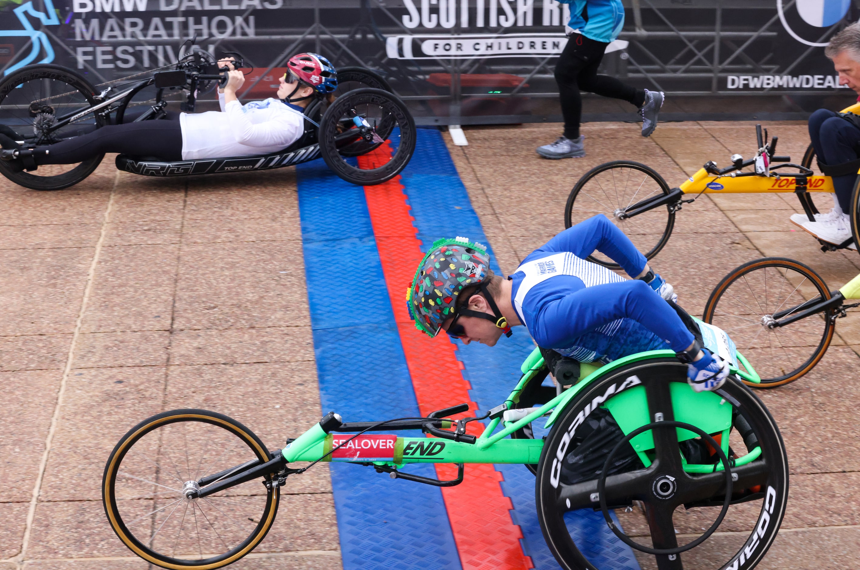 Wheelchair competitors cross the start line in front of Dallas City Hall as part of the BMW...