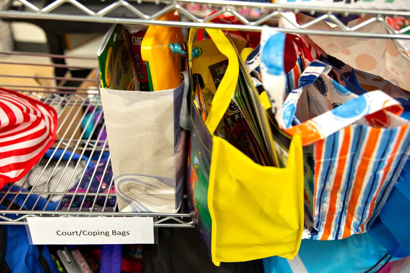 Amid a supply closet filled with clothes and toys, a shelf of "court/coping bags" is a stark...