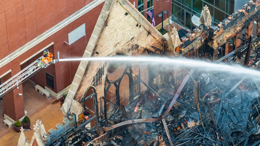 Dallas firefighters spray water on hotspots, after a fire destroyed the First Baptist Church...