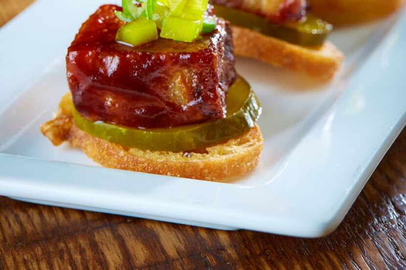 The Sugarbacon is an appetizer of pork belly and spicy pickles on a crostini.