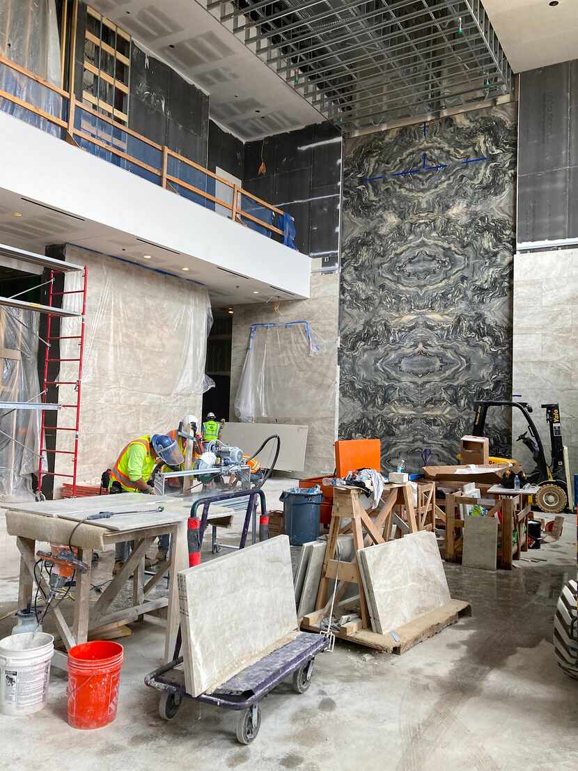 Work crews install stone on the walls of the office lobby in the Weir's Plaza tower. The...