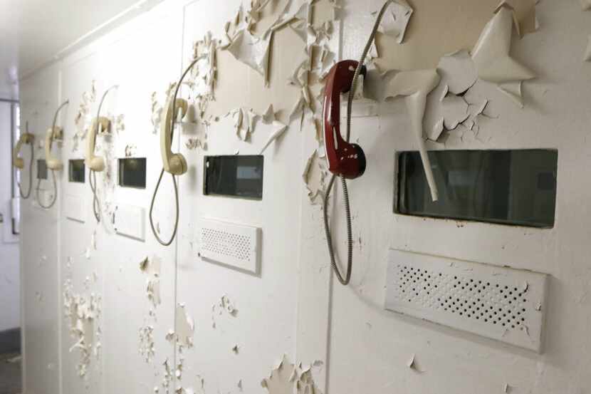Paint peels over visitation phones in a decommissioned jail inside the old Dallas County...