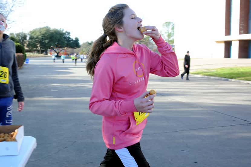 A runner grabs a few donut holes and continues racing in the 2014 Hypnotic Donut Dash at...