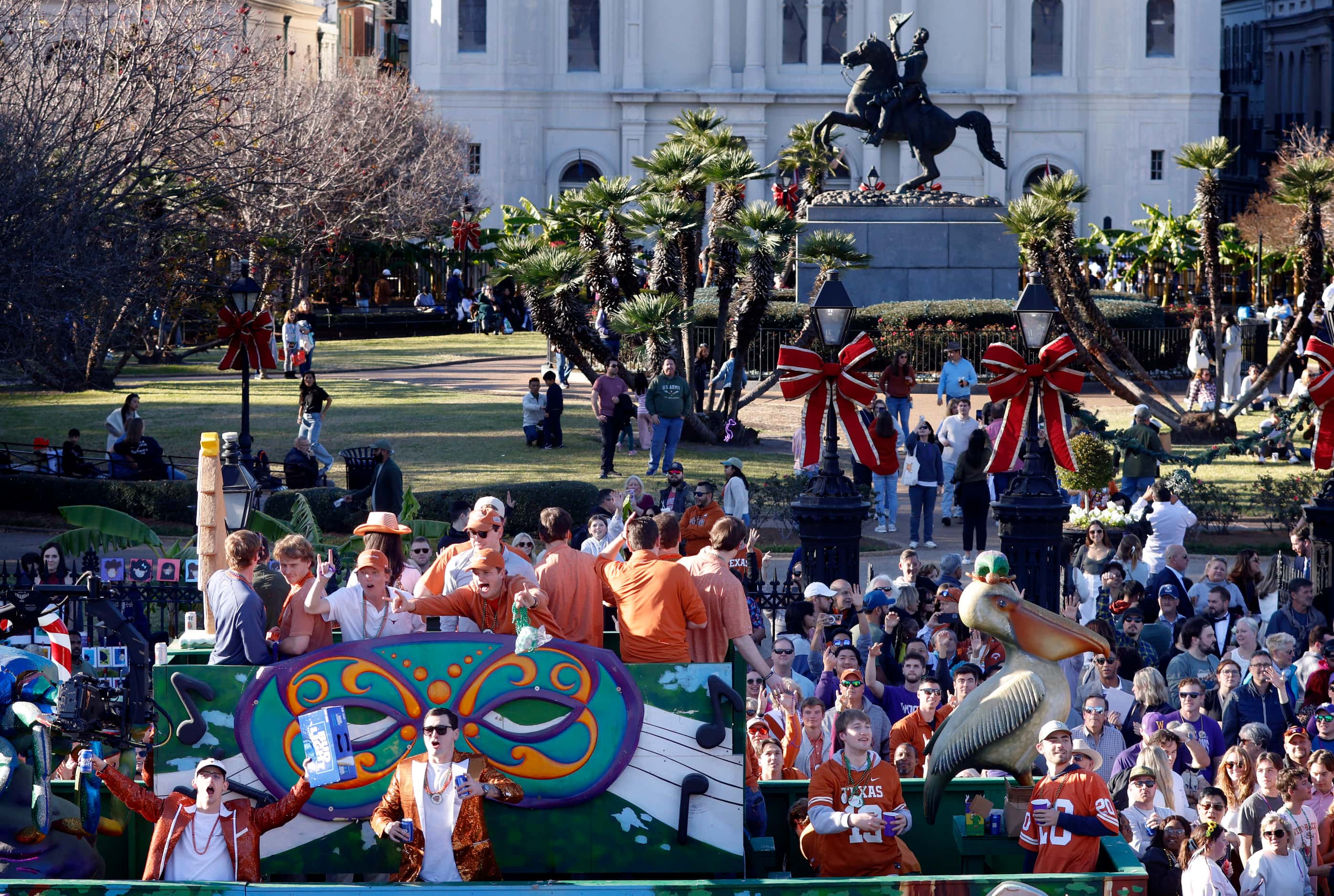 Texas Longhorns fans throw beads and drink beer from atop a large float during the Mardi...