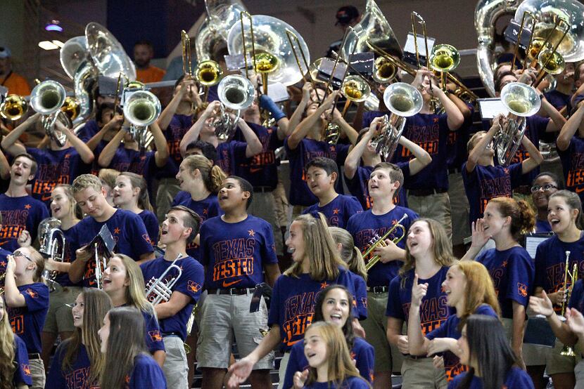 Wakeland High School marching band students react to a play on the field at a varsity...