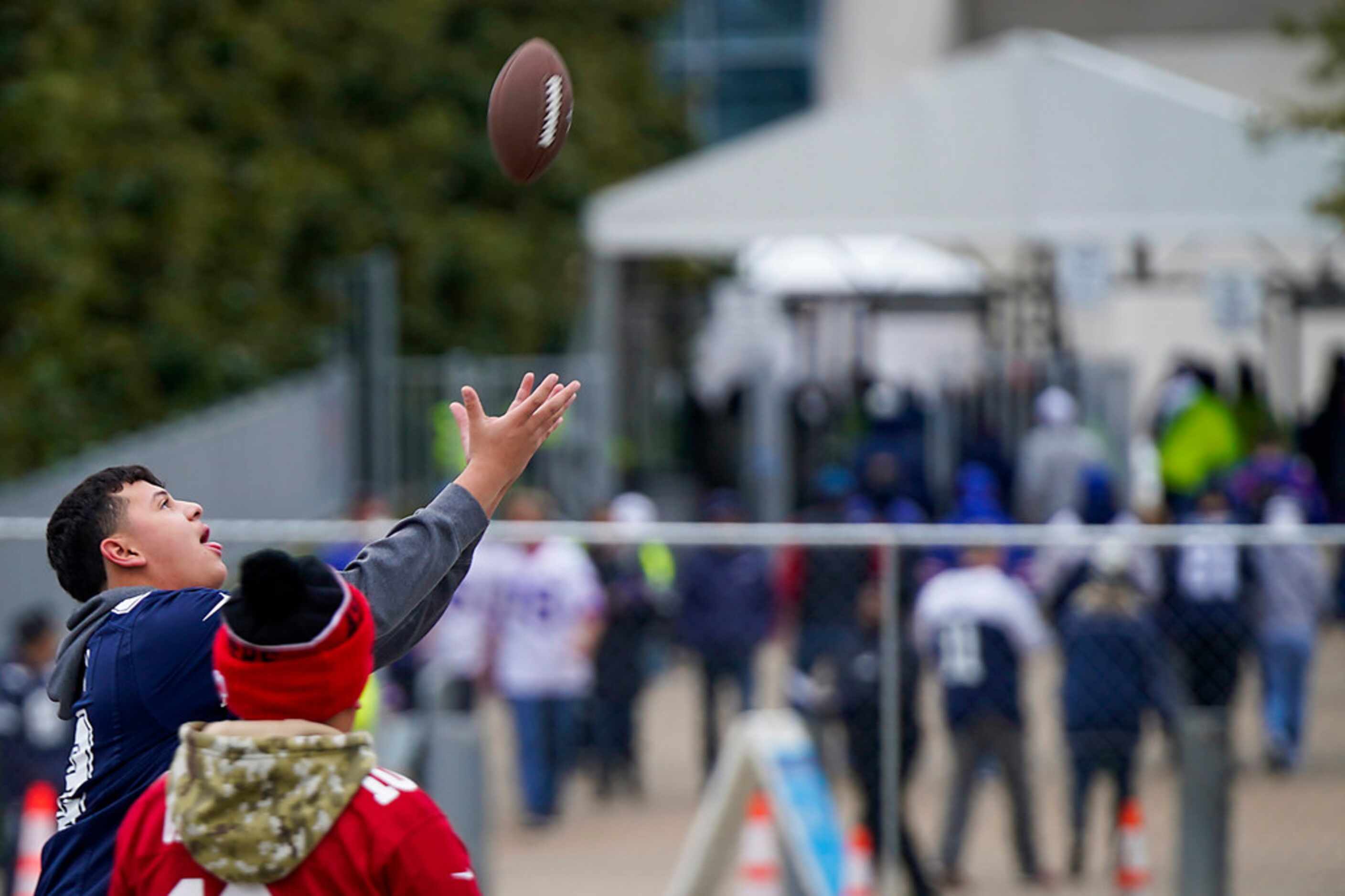Fans toss a football in the parking lot as they tailgate before an NFL football game between...