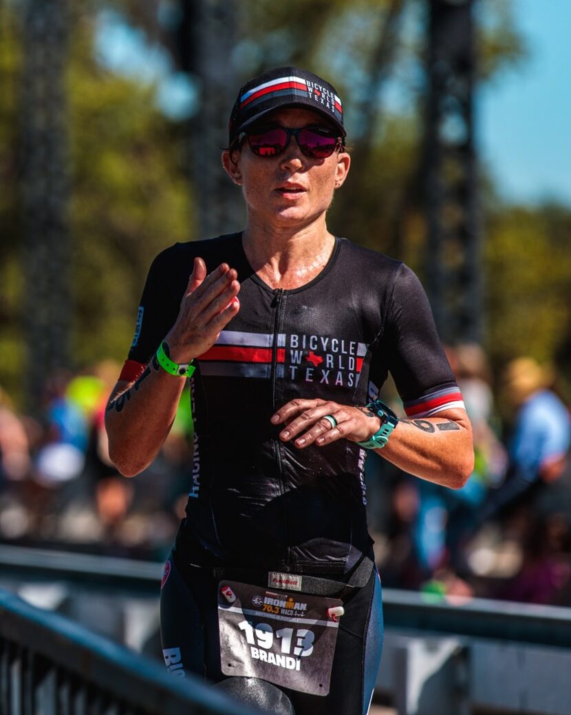 Brandi Grissom Swicegood blows a kiss to her husband and daughter during the run portion of...