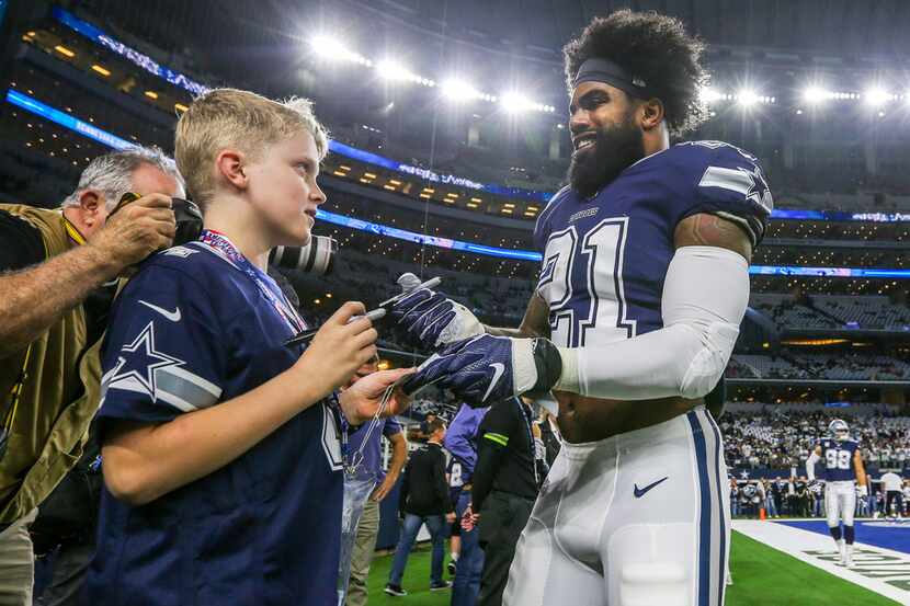 Dallas Cowboys running back Ezekiel Elliott (21) signs a memorabilia before an NFL game...