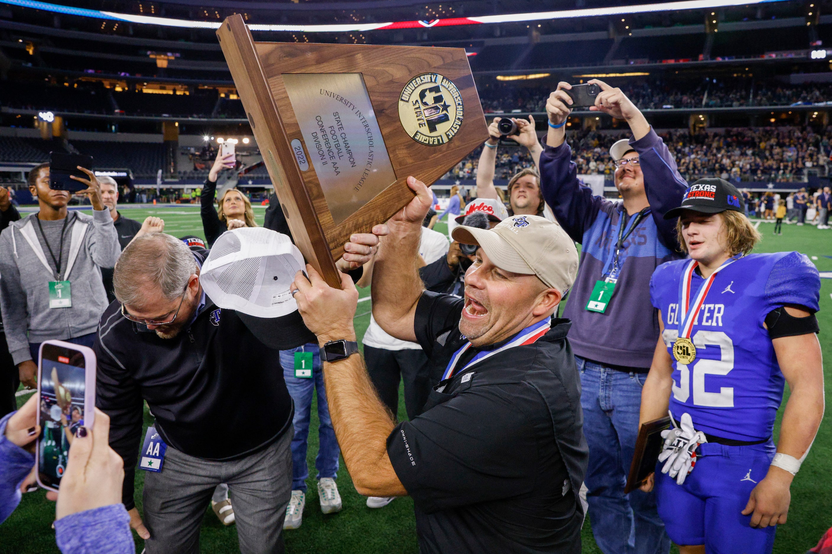 Gunter head coach Jake Fieszel raises the Class 3A Division II state championship trophy...