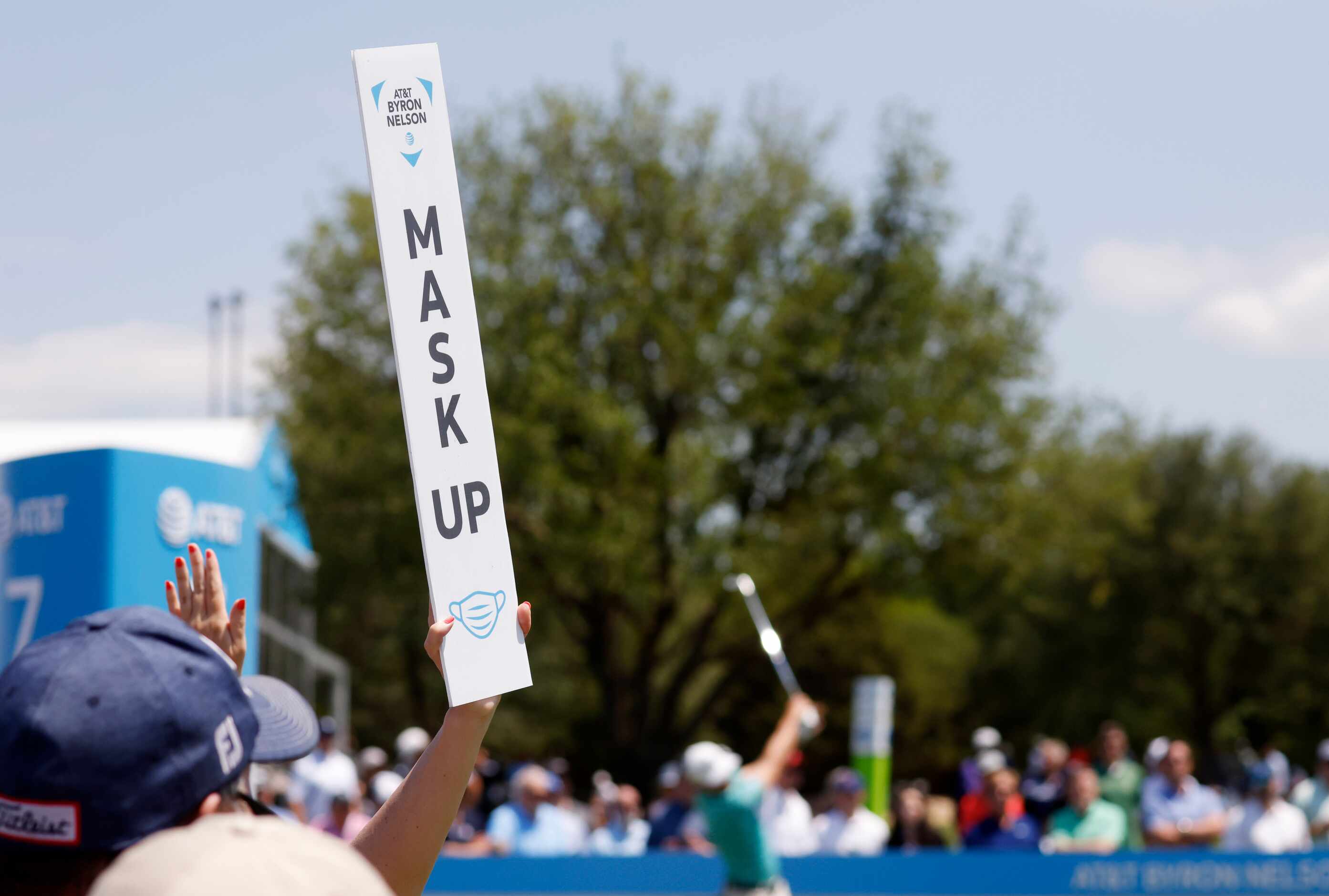 A mask up sign is held as Sam Burns tees off on the 7th hole during round 2 of the AT&T...