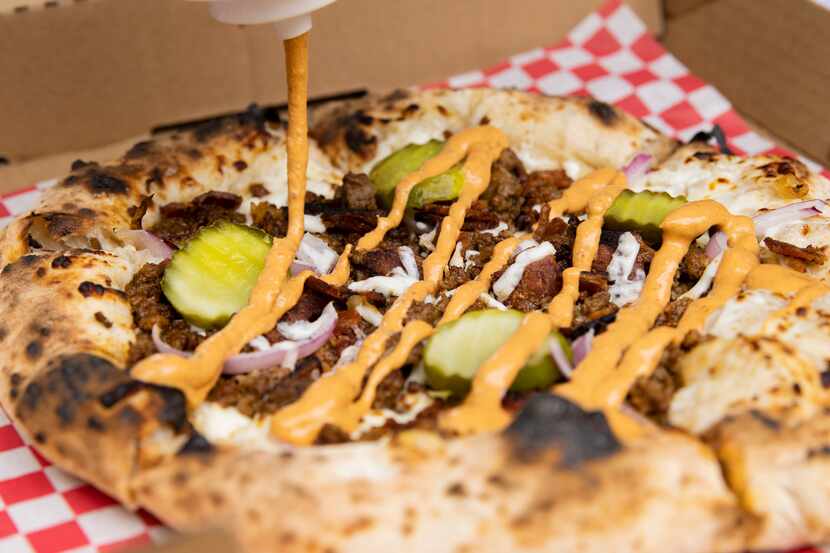 Desmon Coleman, owner of Hustle Town Pizza, prepares a hamburger pizza at Hop and Sting...