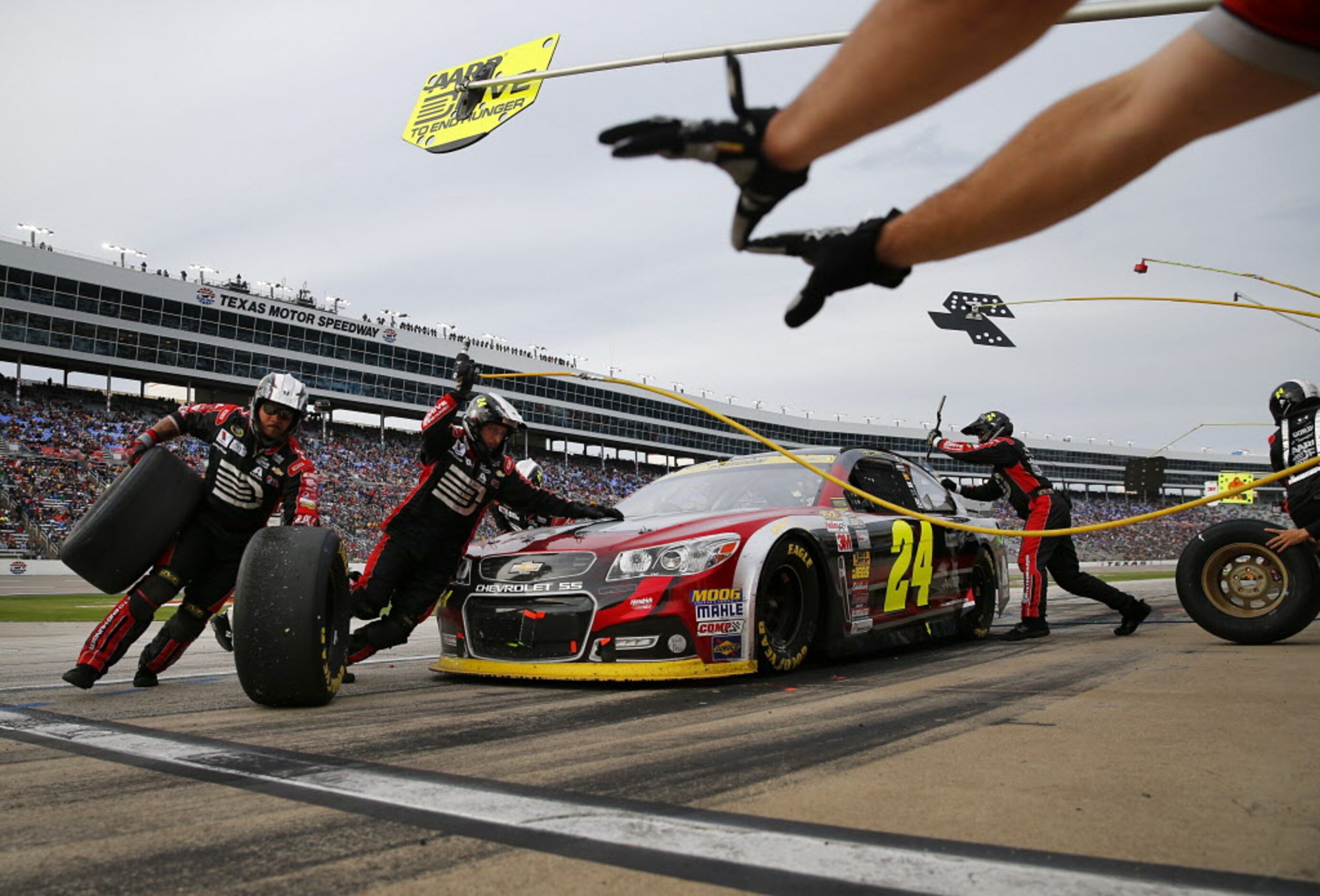 Sprint Cup Series driver Jeff Gordon (24) receives a four-tire change from his crew during...