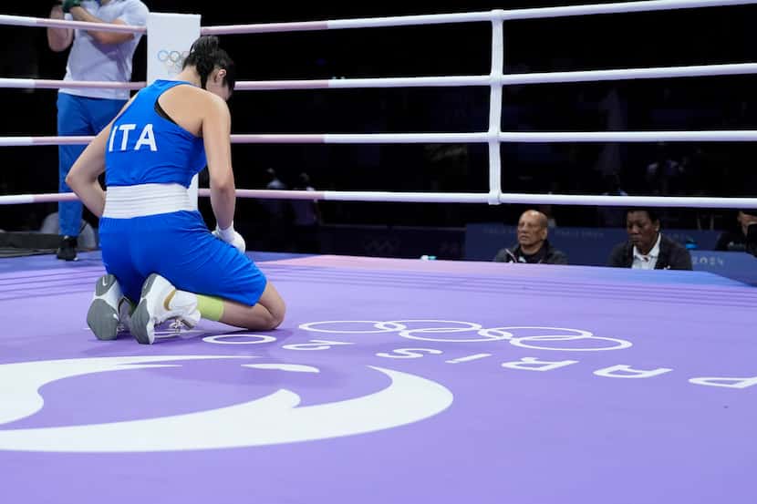 Italy's Angela Carini kneels in the ring after abandoning her fight against Algeria's Imane...