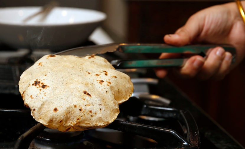 Sapna Punjabi-Gupta finishes off a roti on the open flame to create a puffed phulka.