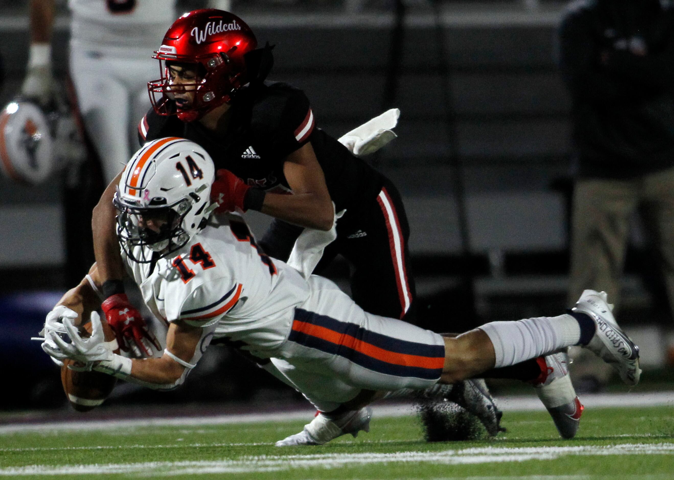 Dallas Woodrow Wilson defensive back Ricky Villalobos (14), top, reaches in to force the...