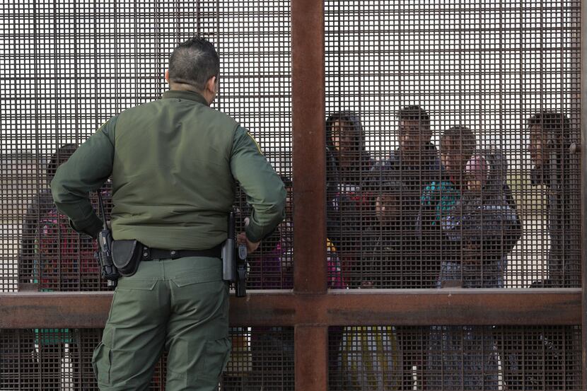A U.S. Border Patrol agent speaks with Central American immigrants at the border fence after...