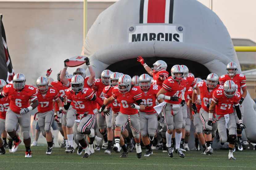 Flower Mound Marcus' players take the field through the team's inflatable tunnel before a...