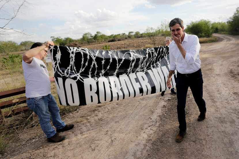 Texas Democratic Congressman Beto O'Rourke, right, passes a "No Border Wall" sign during a...