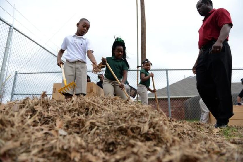 
Second-grade students Jumoke Henry (left) and Jamyah Anderson rake leaves to be used for...