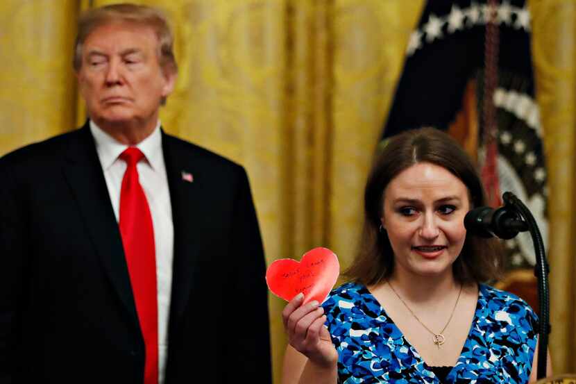 Polly Olson holds up a heart that says "Jesus Loves You" during an event with President...