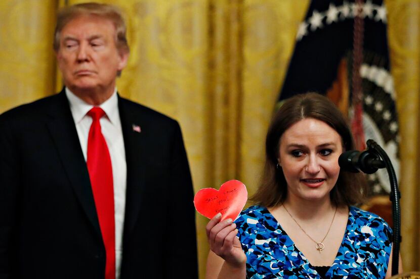 Polly Olson holds up a heart that says "Jesus Loves You" during an event with President...