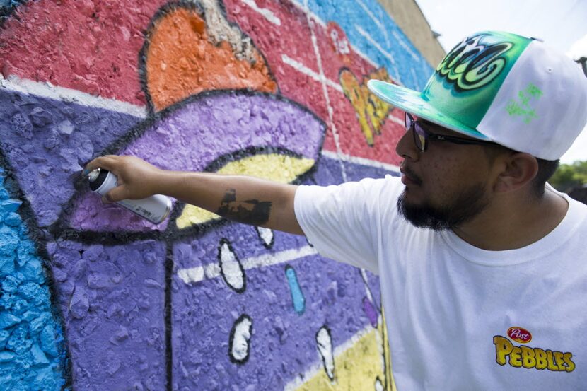 Artist Daniel Yanez uses spray paint to add to the finishing touches of the mural at Oak...