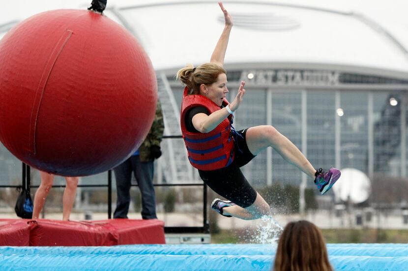 A Wipeout Run participant gets bumped off of an inflatable balance beam by a large tethered...