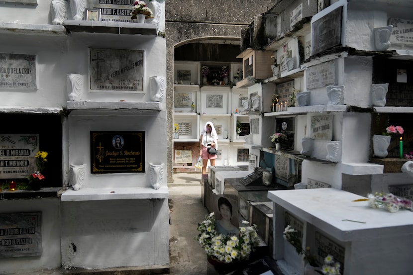 A woman stands in between apartment-type tombs at Manila's North Cemetery, Philippines as...